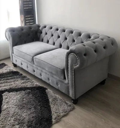 Sofá Chesterfield gris terminado en salón con alfombra