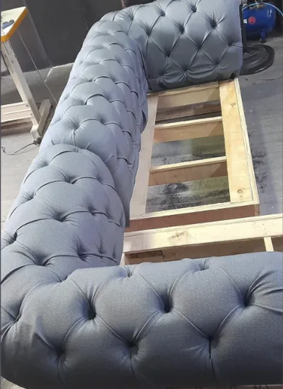 Sofá Chesterfield gris capitoné en proceso de montaje en el taller