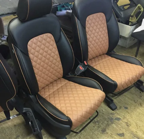 Asientos delanteros de coche tapizados en piel negra con detalle en cuero color tabaco y costura tipo rombo