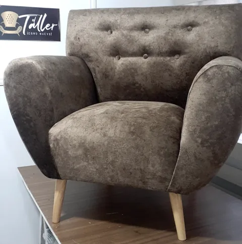 Interior de Tapicería El Taller en Elda con un sillón tufted marrón y el cartel de la marca al fondo